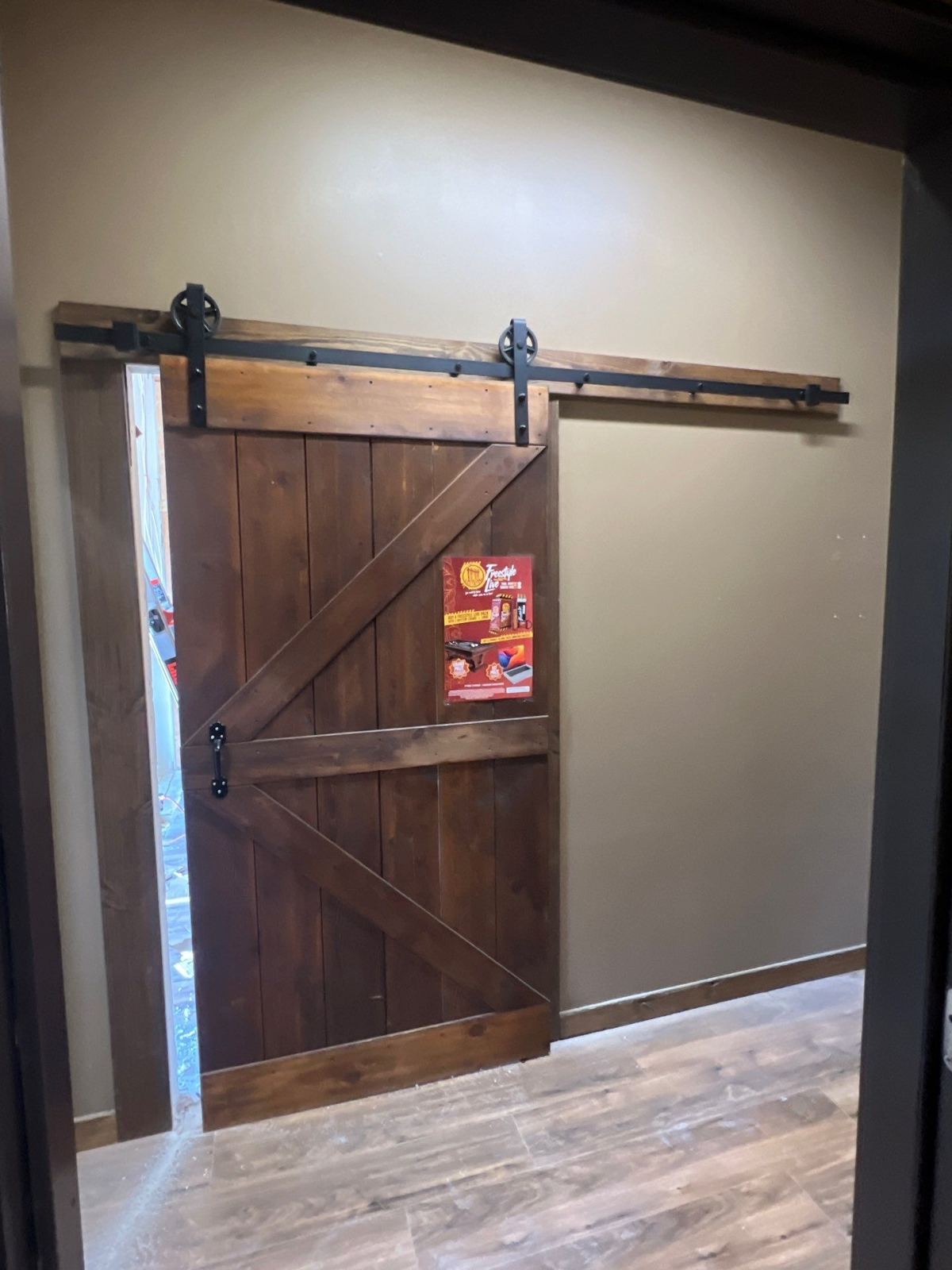 Finished sliding barn door on black hardware in the expanded space